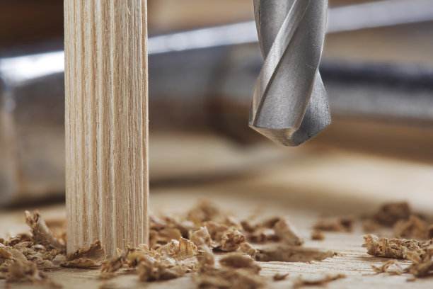 钻头在橡木木板上钻孔，用于木销子。图片下载