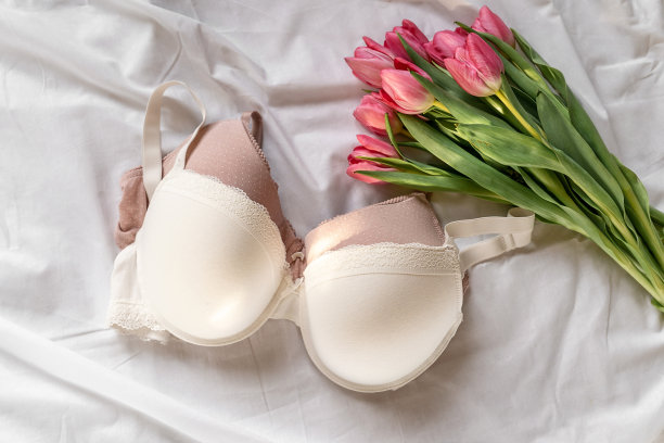 白色和粉色的胸罩，床上有粉红色的郁金香。女性柔情内衣、内衣。俯视图，特写。平面布局，美容博客或社交媒体的最小概念。情人节，妇女节的礼物图片下载