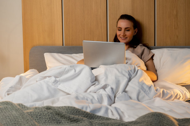 年轻女子晚上在床上使用笔记本电脑。睡眠障碍问题图片下载