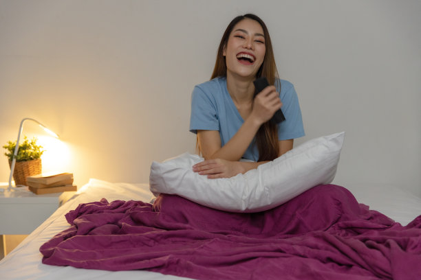 女人在卧室看电视，笑。图片下载