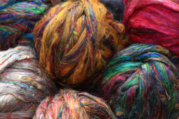 来自印度的回收莎丽丝纺织纤维的彩色球，准备在传统的纺车上纺纱作为一种爱好。图片下载