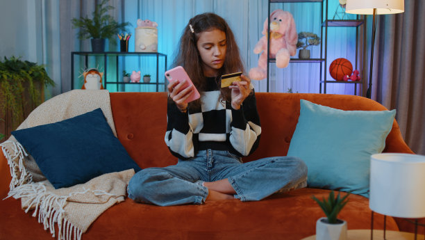 可爱的小女孩用信用卡和智能手机转账，网购图片下载