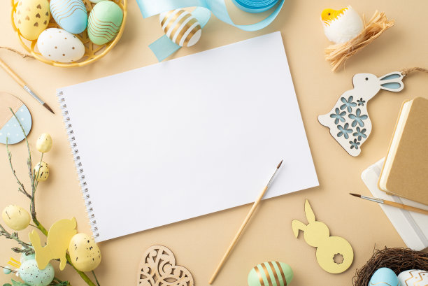 复活节的概念。相册的顶部视图照片刷子彩色复活节彩蛋在碗木制装饰蓝丝带鸡窝记事本和复活节花束在孤立的米色背景与复制空间图片下载