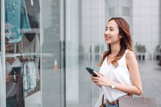 美丽的亚洲女性女子女孩拿着购物袋，散步享受微笑，在百货商场的橱窗外购物户外时尚的生活方式图片下载