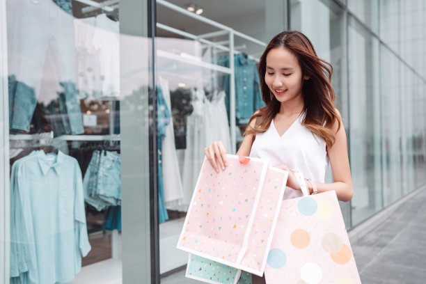 美丽的亚洲女性女子女孩拿着购物袋，散步享受微笑，在百货商场的橱窗外购物户外时尚的生活方式图片下载