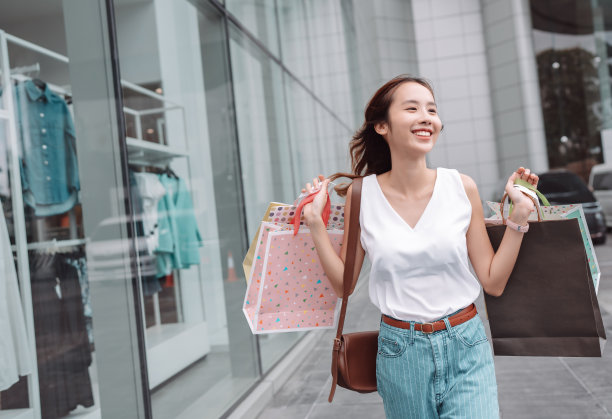 美丽的亚洲女性女子女孩拿着购物袋，散步享受微笑，在百货商场的橱窗外购物户外时尚的生活方式图片下载