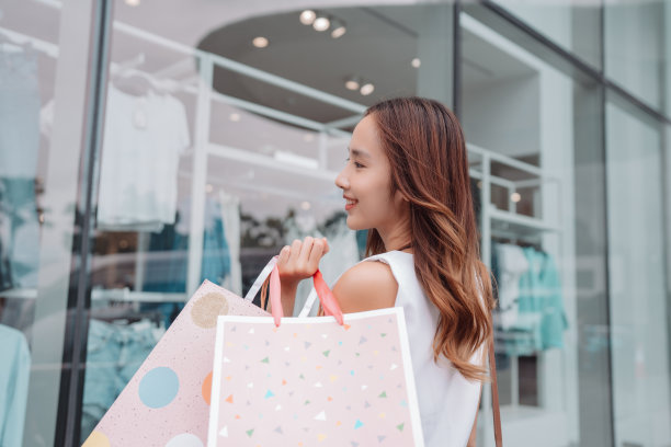 美丽的亚洲女性女子女孩拿着购物袋，散步享受微笑，在百货商场的橱窗外购物户外时尚的生活方式图片下载