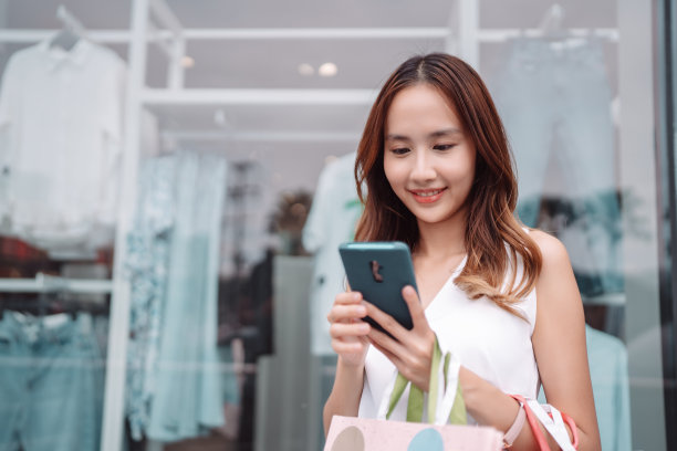 美丽的亚洲女性女子女孩拿着购物袋，散步享受微笑，在百货商场的橱窗外购物户外时尚的生活方式图片下载