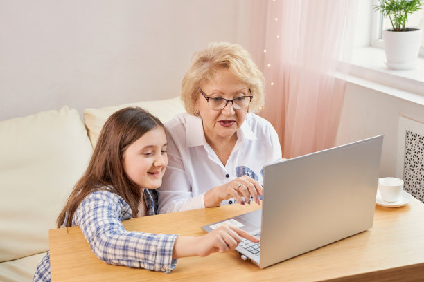 成年孙女教年迈的祖母使用笔记本电脑图片下载
