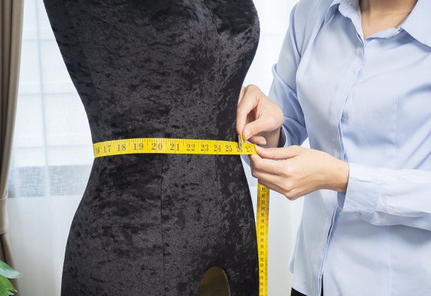 女性时装设计师，服装创意设计师在人体模型上测量尺寸。图片下载