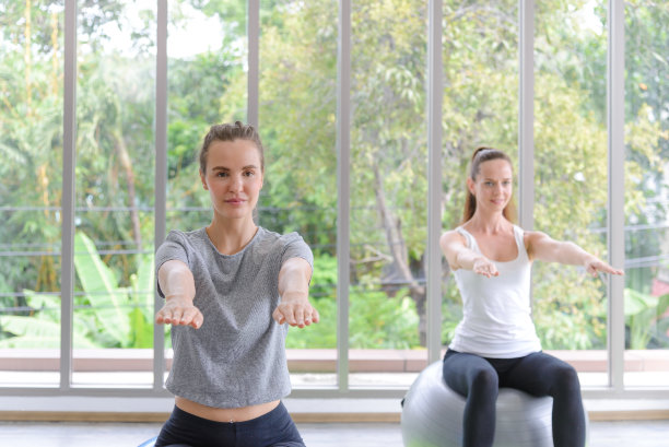 白人妇女坐在健身球上保持平衡。健身，运动，训练和人的概念。图片下载