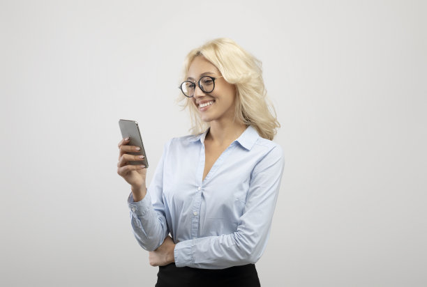 年轻女企业家的肖像与手机工作在线或与客户聊天在灯光工作室背景图片下载