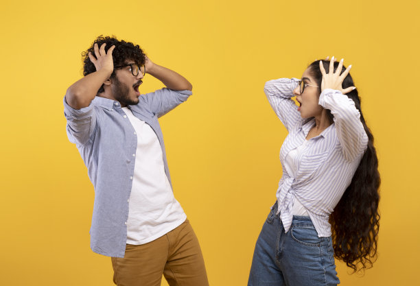 一名震惊的印度女士和她的男朋友张着嘴互相看着对方，感到惊讶，摸着头图片下载