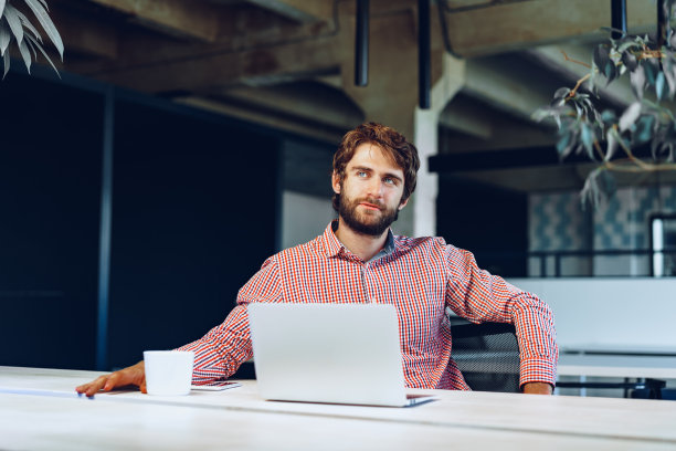 一位困惑的商人坐在办公室的工作桌旁图片下载