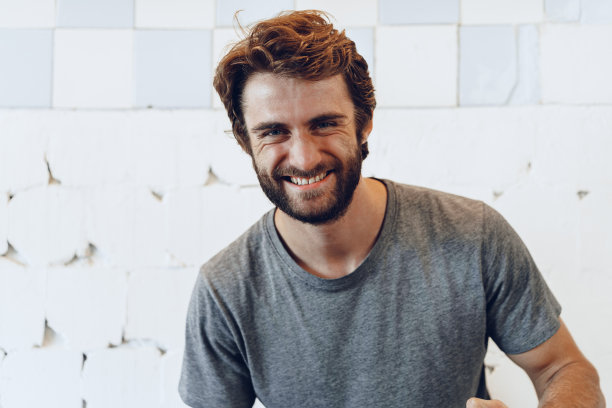 高兴快乐的大胡子男人靠在粗糙的墙上图片下载