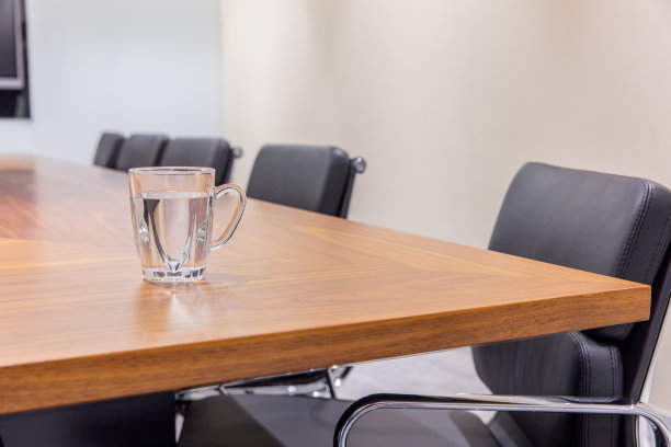 近距离的会议室，桌子上放着水杯，扶手椅和大显示器图片下载