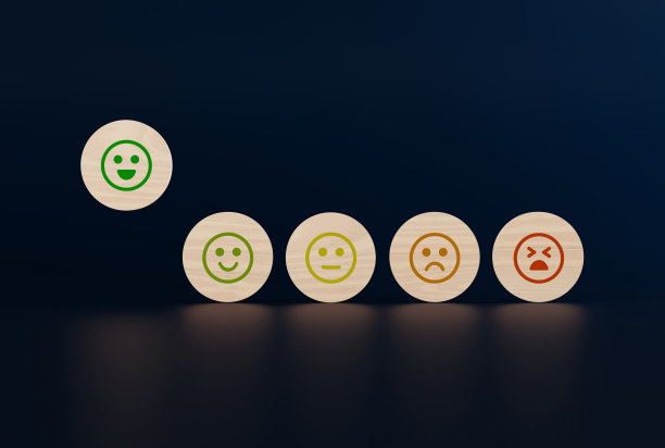 木制的圆盘上有从快乐到悲伤的面孔图标，一只手拿起一个有图标的圆盘。图片下载