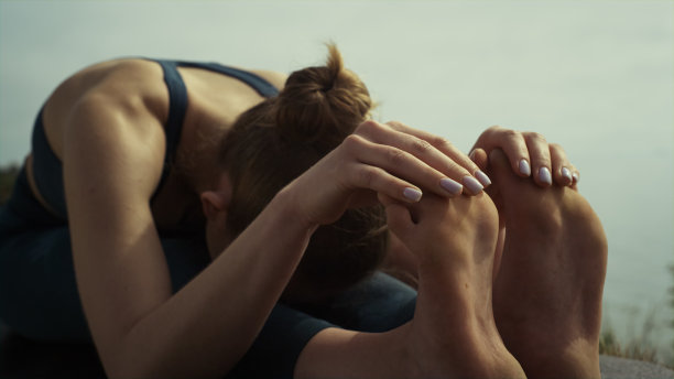 放松女运动员弯腰坐瑜伽姿势。女孩在练习体操图片下载