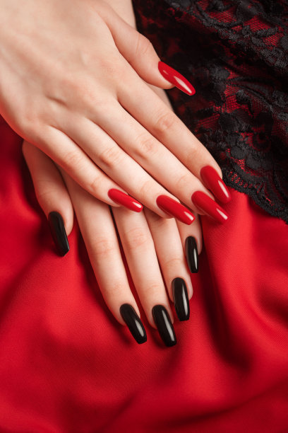 一个年轻女孩的手，指甲上有黑色和红色的美甲图片下载