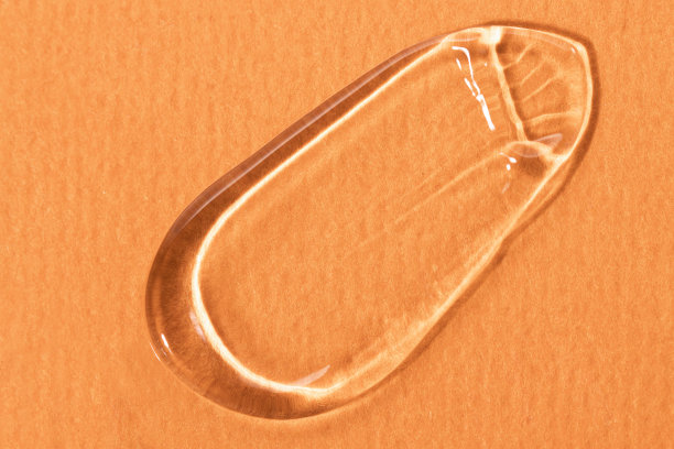 涂抹的凝胶透明化妆品产品特写上的橙色背景顶视图。保湿、护肤。图片下载