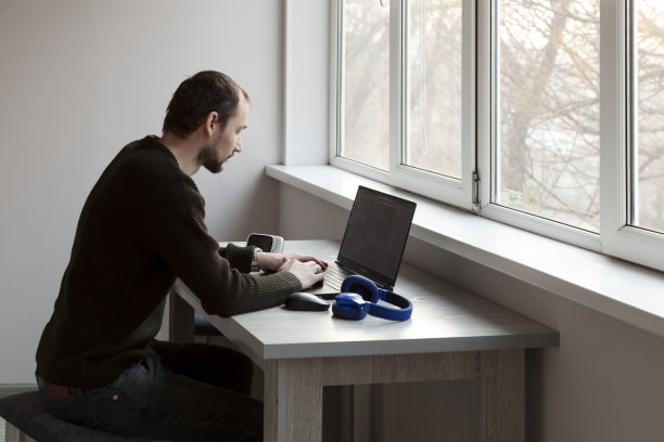 年轻人坐在家里的桌子上用笔记本电脑工作图片下载