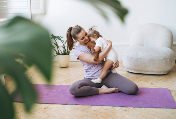年轻女子健身妈妈在她的怀里做健身垫在家里图片下载