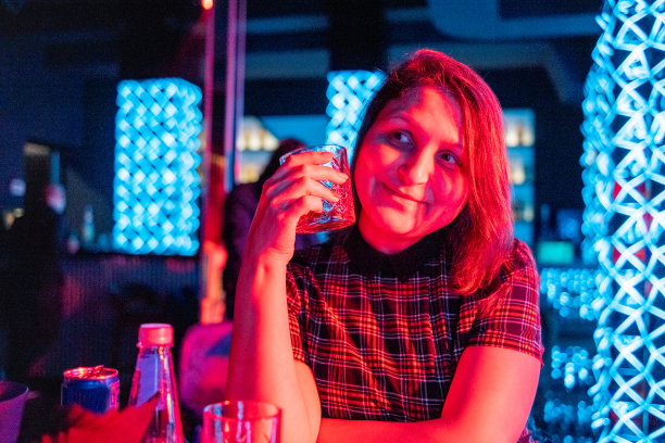 年轻快乐的女人与玻璃杯在夜总会。图片下载