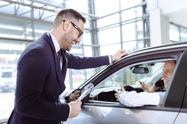 销售人员在汽车展厅与男顾客交谈图片下载