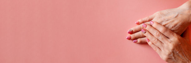 成人修指甲。一个成年女子的手与一个美丽的美甲在淡粉色的背景。手部修剪自然，清洁成人肌肤。高分辨率图片下载