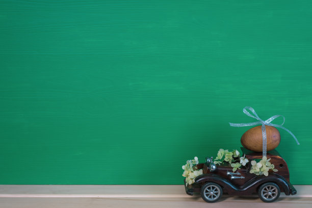复活节假期。一辆棕色的木制玩具复古车载着一颗鸡蛋。复活节卡片和复古车图片下载