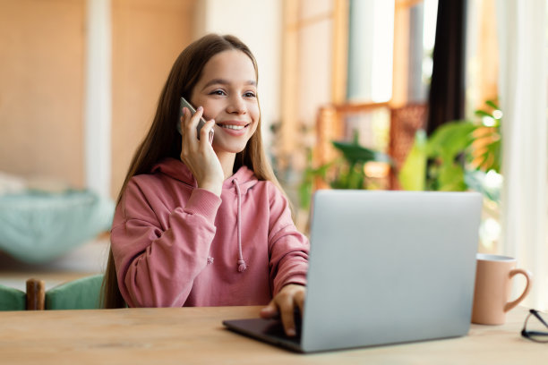 快乐的少女打电话和笔记本电脑上打字，坐在家里，在网上上课休息图片下载