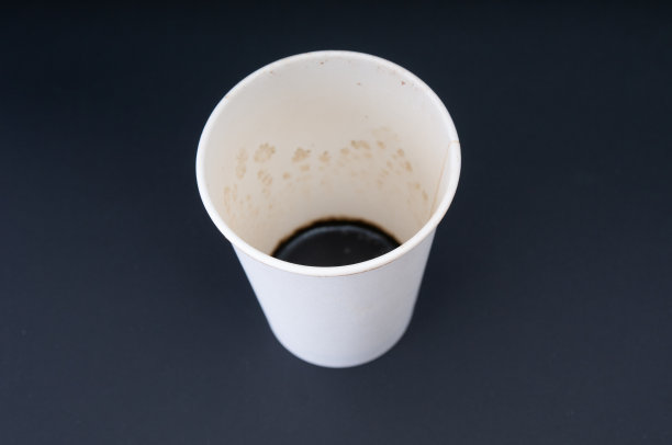 黑色背景上有咖啡残渣的一次性纸杯。前集中图片下载