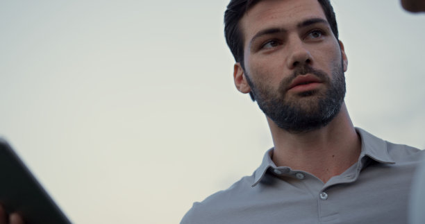 男子在户外看着平板电脑屏幕。性感的家伙在网上谈论高尔夫球场。图片下载