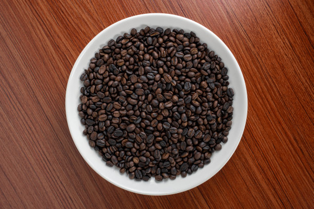 咖啡豆被放在一个盘子里，背景是一块木板。有地方写文字什么的。图片下载