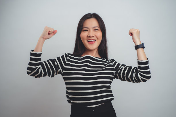 亚洲女性快乐的微笑显示出强烈的姿态孤立在白色背景。图片下载