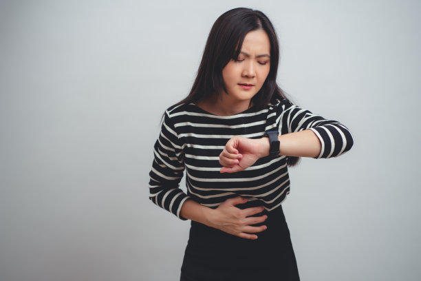 患有胃痛的亚洲妇女孤立地站在白色背景上。图片下载