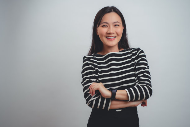 亚洲女人快乐地微笑着站在白色背景上。图片下载