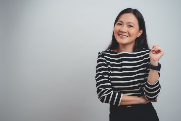 亚洲女人快乐地微笑着站在白色背景上。图片下载