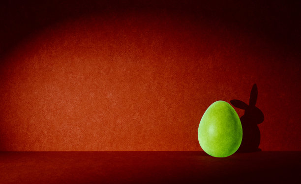 黄色的彩蛋前面有兔子的影子，红色的背景，贺卡，概念艺术，俏皮，快乐图片下载