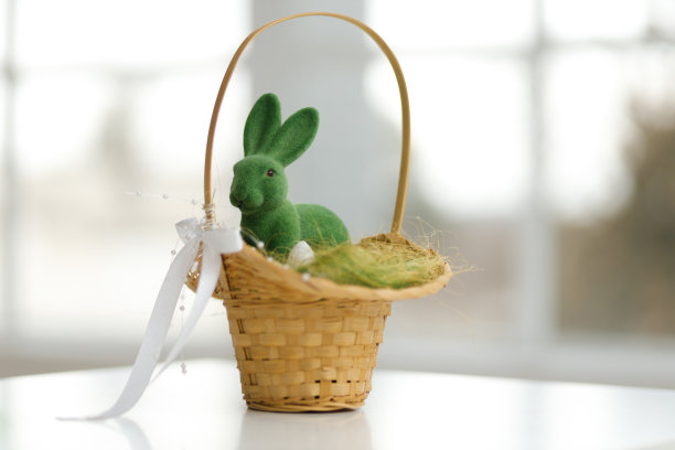 复活节兔子在篮子里。干草上有绿叶的篮子。复活节假期概念背景。复制空间，白色背景。图片下载