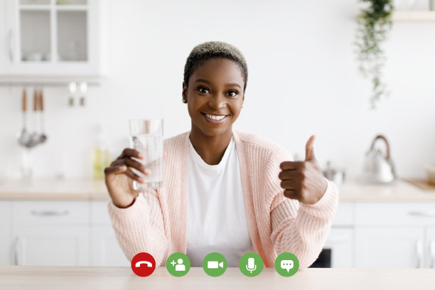 快乐的千禧一代黑人女性拿着一杯干净的水，在极简主义的厨房内部竖起大拇指图片下载