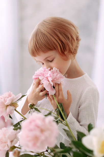 一个6-7岁的女孩穿着白色的裙子，手里拿着一朵花图片下载