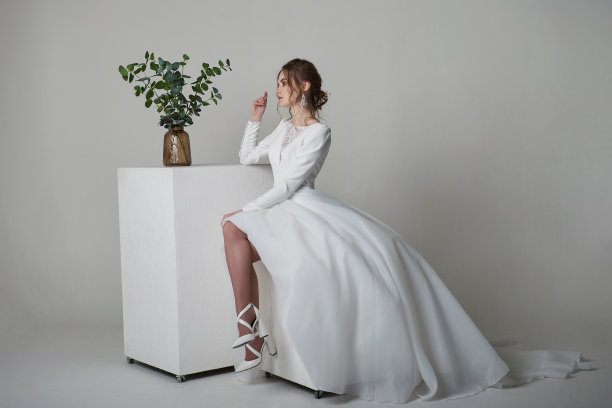 一个美丽的年轻新娘模型长蕾丝礼服在极简主义的白色工作室内部。婚礼摄影。图片下载