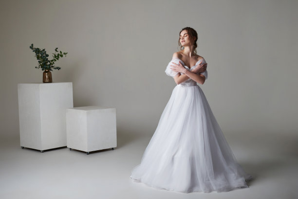 一个美丽的年轻新娘模型长蕾丝礼服在极简主义的白色工作室内部。婚礼摄影。图片下载