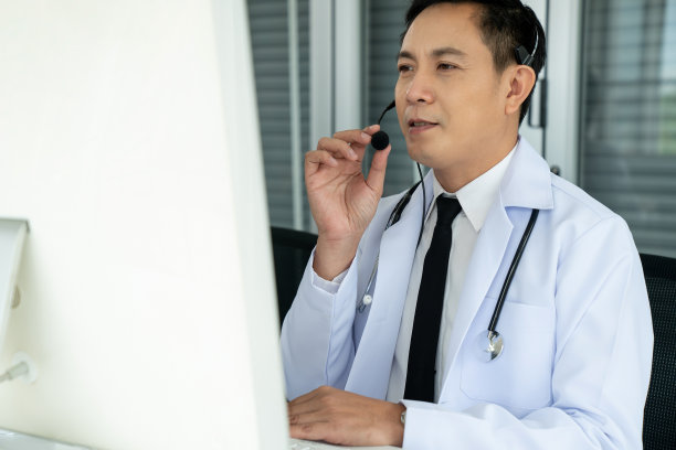 医生戴着耳机在诊所或医院积极视频通话。远程保健和远程医疗服务的概念。图片下载