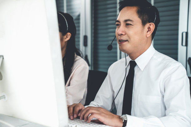 商人戴着耳机在办公室积极工作。呼叫中心、电话营销、客服为客户提供电话视频会议服务。图片下载