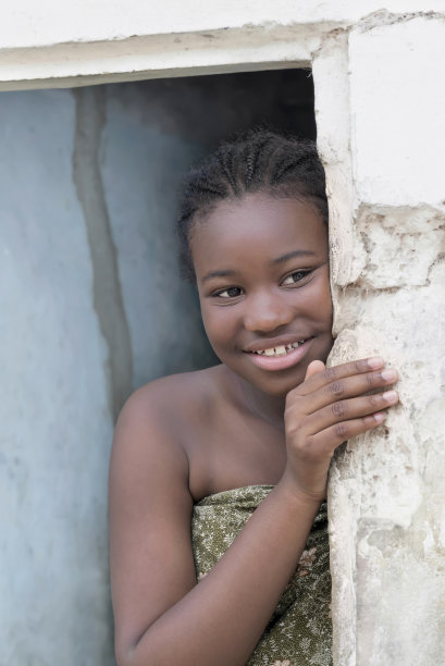 年轻的非洲女孩站在家门口，微笑的表情，照片图片下载