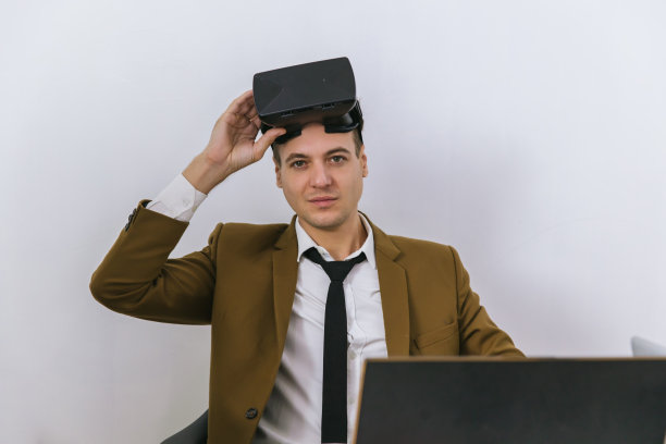 戴着VR头盔的商人。男子使用VR眼镜玩网络游戏。商务人士坐在带有安全接口的办公大楼内，使用虚拟现实耳机图片下载