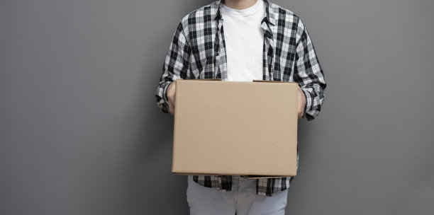 男员工在仓库里拿着一个纸板包裹图片下载