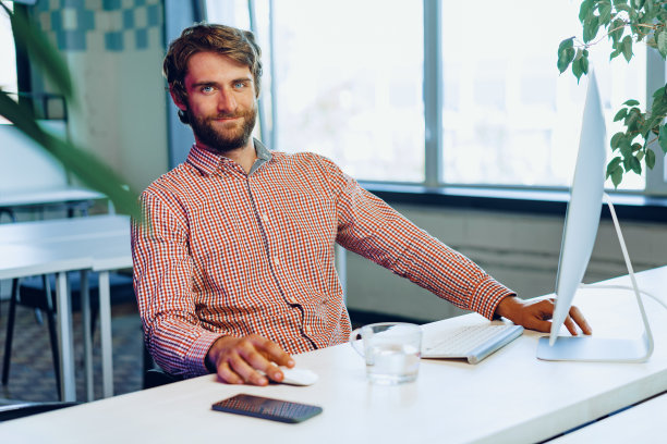 年轻的大胡子商人在一个现代化的办公场所使用电脑图片下载